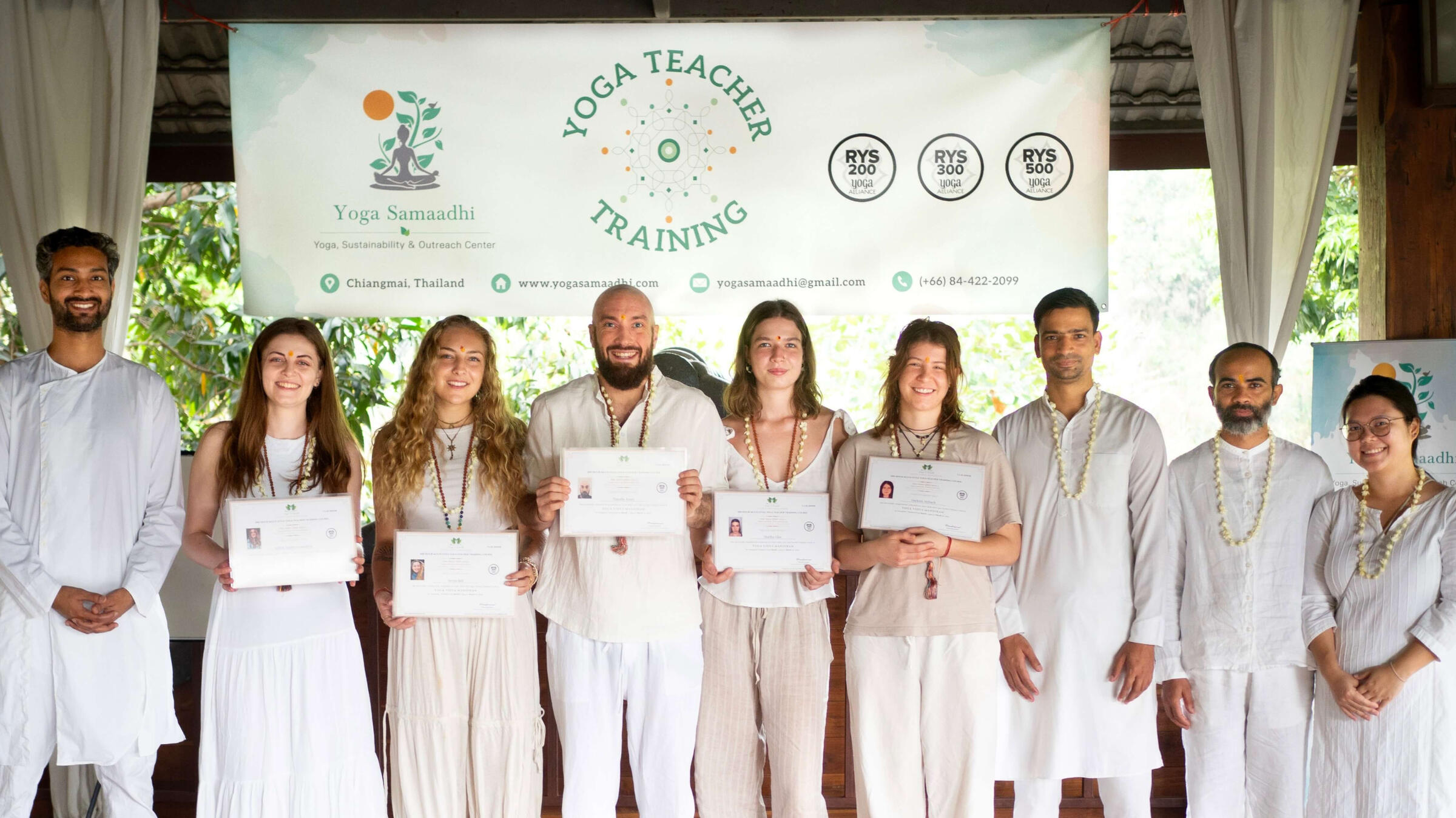 A group of people with their yoga teacher training certificates upon completion at Yoga Vidya Mandiram