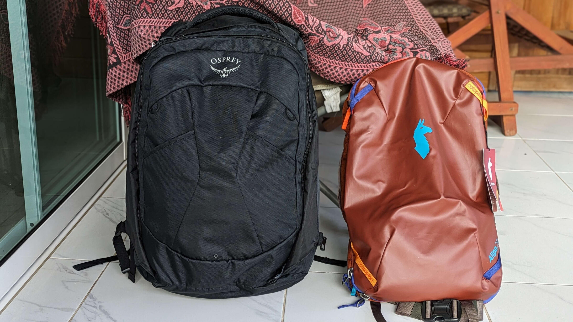 The Cotopaxi Allpa 28 litre Travel Pack next to the Osprey Farpoint 40 litre backpack