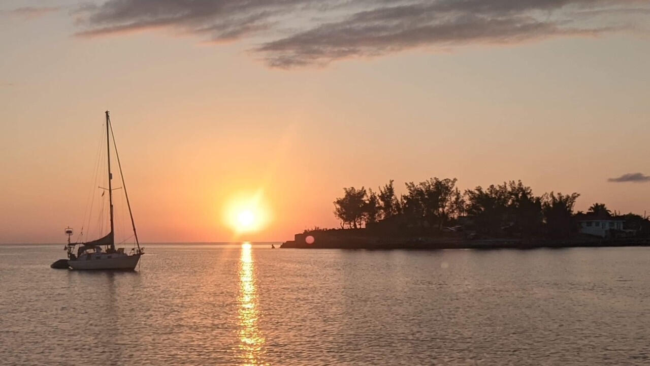 A picture of a boat with a sunset by Craig Savageau, sailing around the world